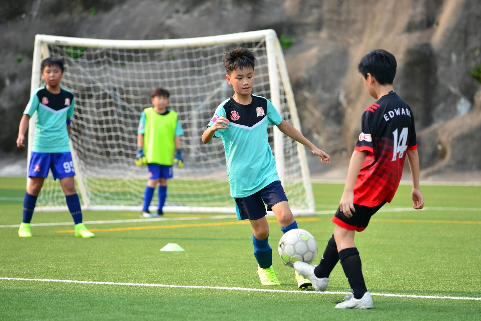 Boys playing soccer during a team training session outdoors on a sunny day.